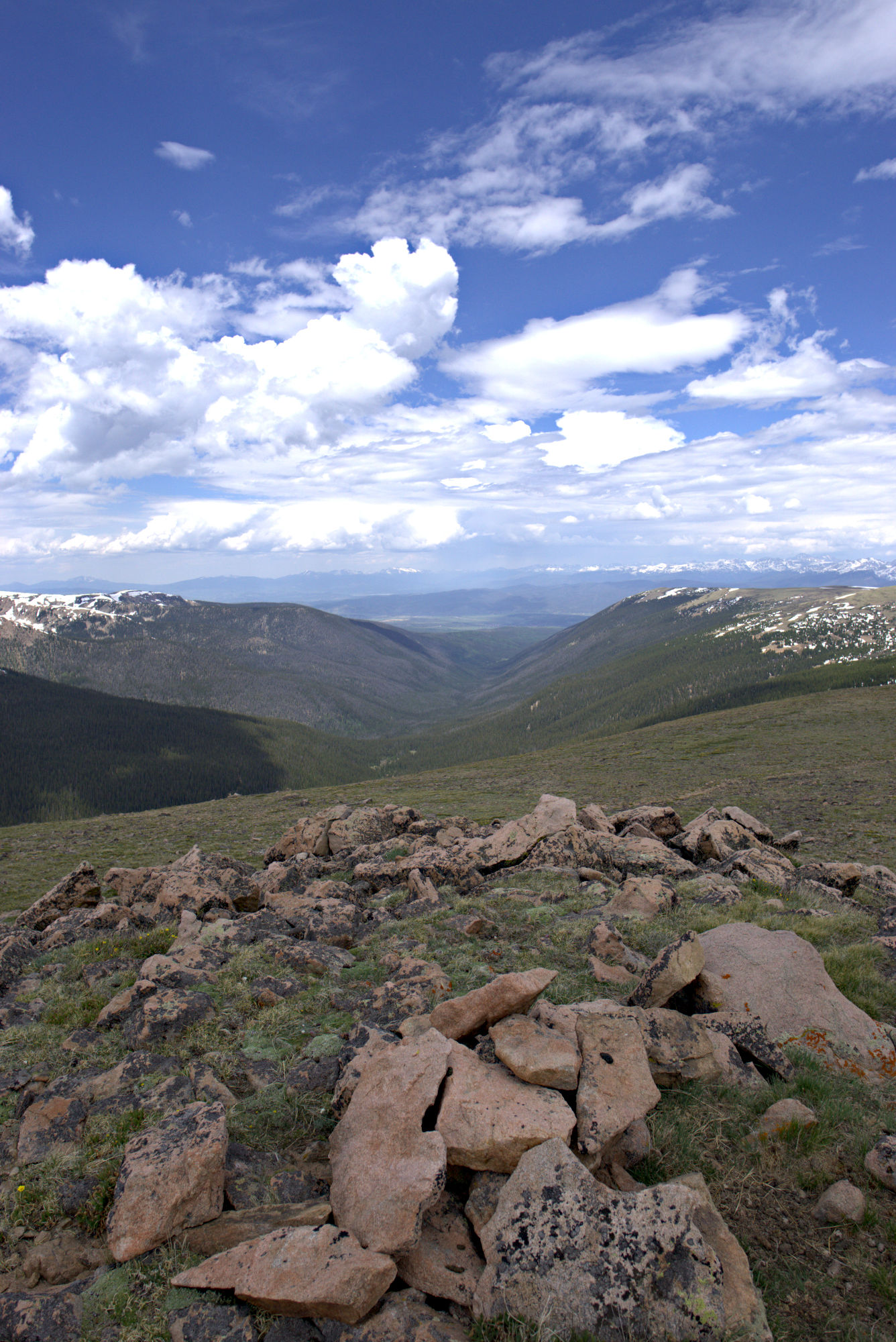 Grasslands and valleys, viewed from the top of a mountain. The sky is blue and cloud cover is minimal.